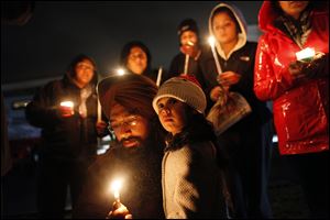 Guramril Singh kneels beside his daughter Eknoor Kaur, 3, during a candlelight vigil outside Newtown High School before an interfaith service with President  Obama. 