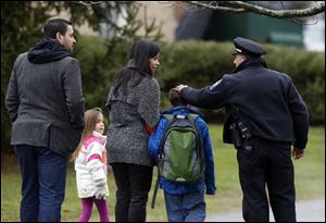 Easton police officer J. Sollazzo greets a returning student as he is walked into Hawley School, today in Newtown, Conn.