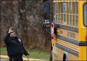 Easton police officer J. Sollazzo waves to returning children as their bus pulls into Hawley School today.