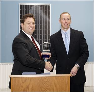 Tom Kimbis of the Solar Energy Industries Association, left, presents the award for Number One Solar Small Town to Napoleon Mayor Ron Behm at Isofoton North America Inc.