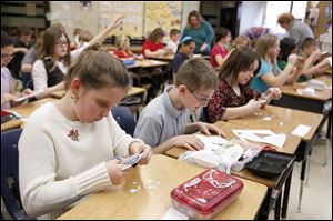 Taylor Zay cuts out a snowflake as she and other students in Mary Riley's fifth grade class at Edgewater Elementary make snowflakes for the Blizzards of Blessings campaign.