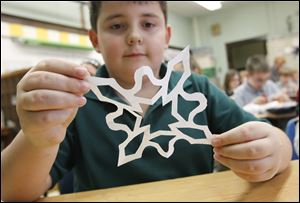 Lucas Gilford admires his handiwork Wednesday as he and other students in Mary Riley’s fifth-grade class at Edgewater Elementary make paper snowflakes. The snowflakes will be hung at Chalk Hill, an elementary school near Newtown, Conn. Sandy Hook Elementary students will start to attend Chalk Hill in January.