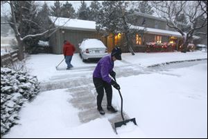 A woman and her husband shovel their walk as a blizzard dropped snow over Boulder, Colo. on Wednesday.