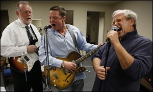 Attorneys Martin Mohler, left, Jim Anderson, and Scott Schwab of Jingle Balls, a rock band com-prising members of the legal establishment and Toledo Municipal Court employees, rehearse at the courthouse before its annual charity performance at 8 p.m. Friday at Mickey Finn’s Pub.