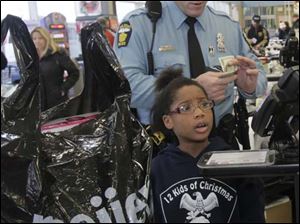Lauren Coats, 9, is a little surprised that they had gone over the dollar amount, but TPD officer Adam Eilerts chipped in with cash. Eilerts had told Coats that he would buy her a present. She and her brother Michael Coats, 8, [not pictured] purchased gifts for others in their family.