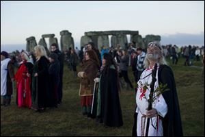 Druid leader Arthur Uther Pendragon, right, looks up as people face east to watch the sunrise by the ancient stone circle of Stonehenge, in southern England, as access to the site is given to druids, New Age followers and members of the public on the annual Winter Solstice.