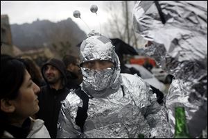 People in alien costumes stand on a street in the town of Bugarach, France.