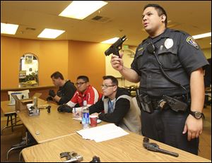 San Diego police officer Jonathan Bamba holds a 9mm Glock hand gun which was turned in during a gun exchange program.  Over 300 guns were exchanged for grocery vouchers. 