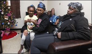 Miyetta Neal, 5, sits on the lap of her mother, Bernice Neal, as Deandre Hooks and Quentorria Snowden talk about the loss of their 1-year-old daughter, Keondra Hooks.