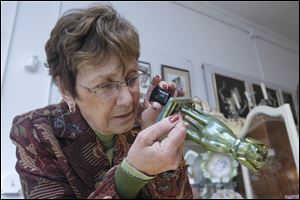 Connie Hoffman inspects markings on the bottom of a small piece at her shop, Adams Street Antiques.