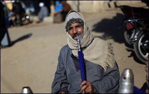 An Egyptian man smokes a water pipe outside a polling station as he waits to cast his vote during the second round of a referendum on a disputed constitution drafted by Islamist supporters of President Mohammed Morsi in Fayoum, about 100 kilometers (62 miles) south of Cairo, Egypt, Saturday, Dec. 22, 2012.(AP Photo/Khalil Hamra)