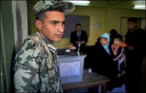 An Egyptian army soldier guards the site of a polling station as a women casts her vote during the second round of a referendum on a disputed constitution drafted by Islamist supporters of president Mohammed Morsi, in Giza, Egypt, Saturday, Dec. 22, 2012.  Egyptians voted on Saturday in the final phase of a referendum on a proposed new constitution that has polarized the nation, with little indication that the result of the vote will end the political crisis in which the country is mired. (AP Photo/Nasser Nasser)