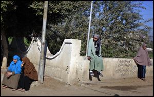 Egyptians sit outside a polling station wait  to cast their votes during the second round of a referendum on a disputed constitution drafted by Islamist supporters of President Mohammed Morsi in Fayoum, about 100 kilometers (62 miles) south of Cairo, Egypt, Saturday, Dec. 22, 2012.(AP Photo/Khalil Hamra)