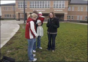 Jessica and Brent Shimman, left, with their daughter Isabel, 11 months, pray with Laura Angel, pastor of The Rock Church, for victims of the shootings in Connecticut. They gathered outside Coy Elementary in Oregon.