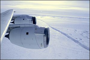 A NASA DC-8 research plane flies over the crack form-ing across the Pine Island Glacier ice shelf in Antarctica. 