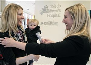 Kari Stausbaugh holds her son Pierce as they are greeted by Christi Rotterdam, executive director of Toledo Children's Hospital Foundation.