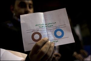 An Egyptian election worker shows his colleagues an invalid ballot while counting ballots at the end of the second round of a referendum on a disputed constitution drafted by Islamist supporters of president Mohammed Morsi at a polling station in Giza, Egypt, Saturday.
