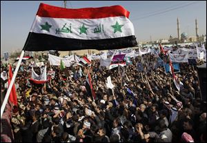 Protesters chant slogans against the Iraq's Shiite-led government as they wave national flags and hold posters of Sunni Finance Minister Rafia al-Issawi during a demonstration in Fallujah, 40 miles west of Baghdad, Iraq, Sunday.
