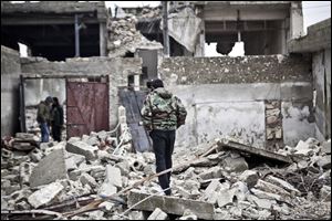 Free Syrian Army fighters walk amid the ruins of a village situated a short distance from an area where fighting between rebels and government forces continues, Saturday.