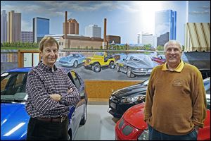 Artist Michael Goettner, left, and David Lawrenz, Nice Car Company owner, show off the mural Mr. Goettner painted at the Ottawa Lake dealership. The 60-foot-by-20 foot work shows local landmarks.