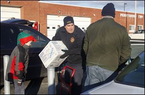 Levi Brice, 8, left, stands ready to help as Matt Homik, center, and  Tom Brice load a car with food. The recipient was among about 100 served Saturday.