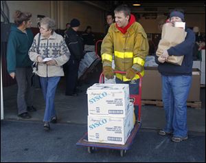 Rossford Fire Explorer Justin Klocko, center, and volunteer firefighter Sara Rynski, right, help distribute food. The annual Operation Bread Basket was Saturday in Perrysburg Township.