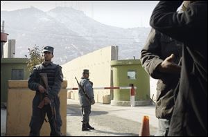 Afghan policemen stand guard outside of Kabul police headquarters, where an American adviser was killed, today.