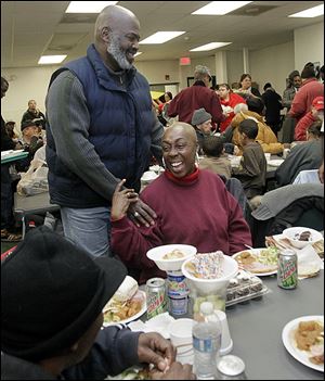 Mayor Mike Bell talks to Mischell Montgomery of Toledo at St. Paul's Community Center during its Christmas dinner for residents and guests.