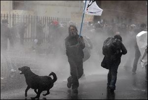 A dog runs in the spray as riot police use water cannons against demonstrators during a protest against the premiere of a documentary about the late Gen. Augusto Pinochet in Santiago, Chile in June.