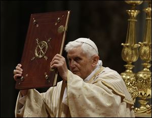 Pope Benedict XVI holds up the book of the gospel as he celebrates the Christmas Eve Mass today in St. Peter's Basilica at the Vatican.