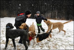 Walker Bowerman, 10, left, and Hughes Bowerman, 6, plays with family dogs in the snow today in Arlington, Texas.