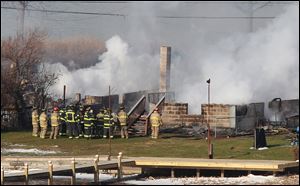 Firefighters gather around a burning house after they were let back into the area to battle the blaze Modnay in Webster, N.Y. 