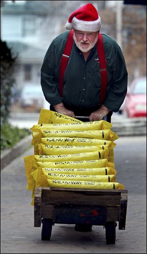 Roger McCreight, a hardware store employee, brings up the remaining bags of rock salt from the basement inventory to stock in the store for customers Monday in Maplewood, Mo., in anticipation of wintry weather. 
