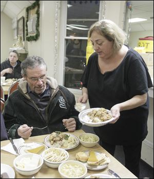 Tom Ward, of Toledo, is served stuffing by Connie Case, of Sylvania Township. The Toledo Gospel Rescue Mission hosts 60 people for Christmas dinner at the facility in Toledo, Ohio on December 25.