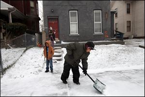 Romeo Roberts, 10, foreground, shovels in front of his home as cousins Demarion Bond, 6, left, and Adrianna Hand, 10, watch in South Toledo. Less than 2 inches of snow fell in Lucas County.