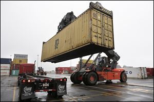 A reach stacker operated by a longshoreman, right, places a shipping container on a tractor trailer truck at the Port of Boston, in Boston. The longshoremen's union may strike if they are unable to reach an agreement on their contract that expires Dec. 29.