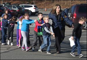 Connecticut State Police lead a line of children from Sandy Hook Elementary School in Newtown, Conn., after a shooting at the school claimed the lives of 20 first graders and six staff members.