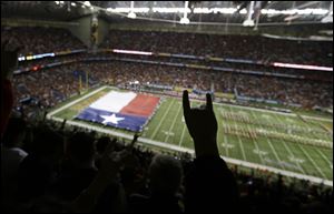 A Texas fans holds up the hook'em horns sign as the Texas band and Texas flag take the field prior to the Alamo Bowl.