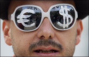 A protester wears glasses with the euro and dollar symbols painted on the lenses before protesting the conservative government's handling of the economic crisis and to demand fresh elections, in Madrid. 