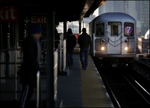 Commuters  walk on the platform as a train enters the 40th St-Lowry St Station, where a man was killed after being pushed onto the subway tracks, in the Queens section of New York.