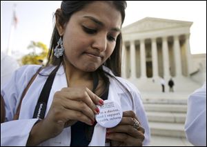 Dr. Sonia Nagda puts on a pin supporting the healthcare reform law as she gathers with other health-care professionals outside the Supreme Court.