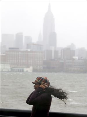 A woman covers her ears in Hoboken, N.J., as Hurricane Sandy bears down on the New York City area.