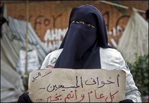 An Egyptian woman holds a poster with Arabic that reads, 