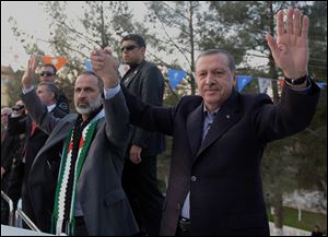 Turkish Prime Minister Recep Tayyip Erdogan, right, flanked by the Syrian opposition coalition leader Mouaz al-Khatib, waves to people as he addresses residents of a Turkish village near the Syrian border in Sanliurfa, Turkey on Sunday.