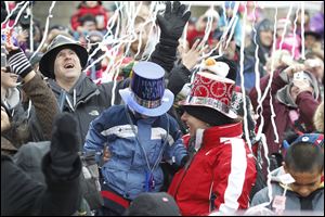 Mike Lencioni, left, of Canton, Mich., his wife, Charlotte, in red, and son Gabriel, 4, celebrate the noon rising of the New Year’s ball at the Toledo Zoo amid confetti and the sound of ‘Auld Lang Syne.’