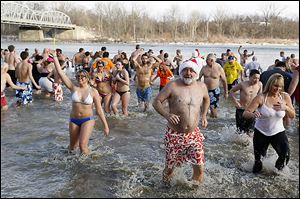 Swimmers hit the cold water of the Maumee River during the 84th annual New Year's Day polar bear plunge in Waterville, Ohio.