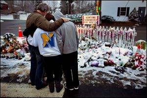 Members of the Rutter family of Sandy Hook, Conn., embrace early Christmas morning as they stand near memorials by the Sandy Hook firehouse in Newtown, Conn. People continue to visit memorials after gunman Adam Lanza walked into Sandy Hook Elementary School in Newtown, Conn., Dec. 14, and opened fire, killing 26, including 20 children, before killing himself. 