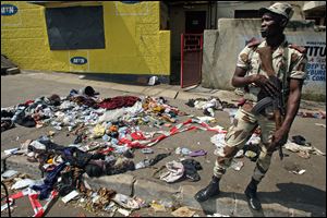 An Ivory Coast troop stands next to the belongings of people involved in a deadly stampede in Abidjan, Ivory Coast, today.