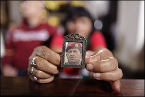 A woman holds an image of Venezuela's President Hugo Chavez as people gather to pray for him at a church in Caracas, Venezuela, on New Year's Eve.