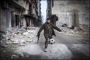 A Syrian rebel plays football today in the Saif al-Dawlah neighborhood of Aleppo, Syria,